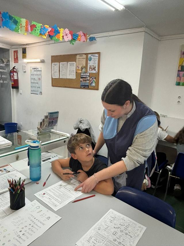 Una educadora ajudant un alumne amb els exercicis
